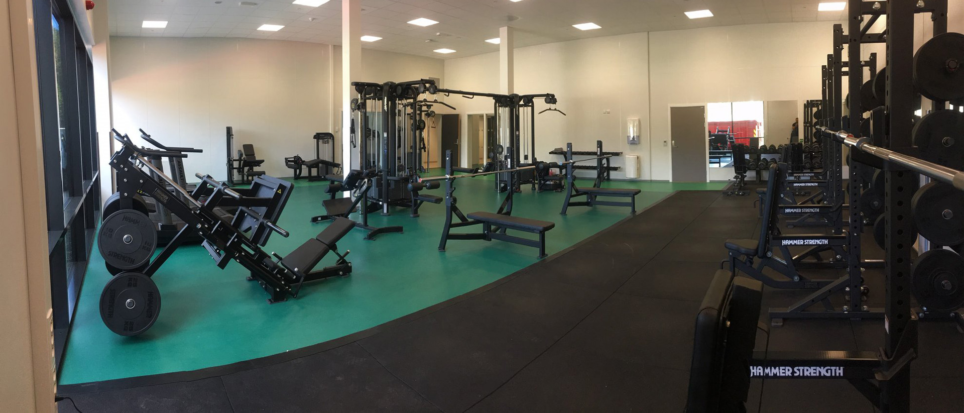 treningsrom med svarte treningsapparater grønt gulv